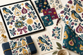 Wild Orchard and Songbirds artwork displayed on a tablet with coordinated fabric, gift packaging, stationery, swatches, and a hang tag.