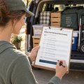 Vendor completing the final driveway checklist beside a packed market vehicle